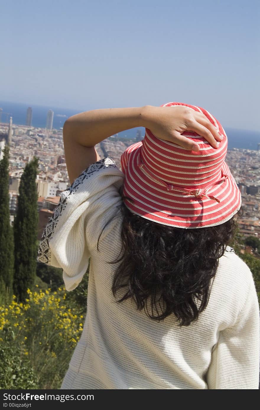 Woman with red and white striped hat over looks a city by the ocean from a mountain. Woman with red and white striped hat over looks a city by the ocean from a mountain.