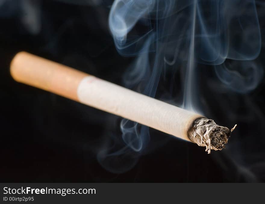 An isolated lit cigarette on black background