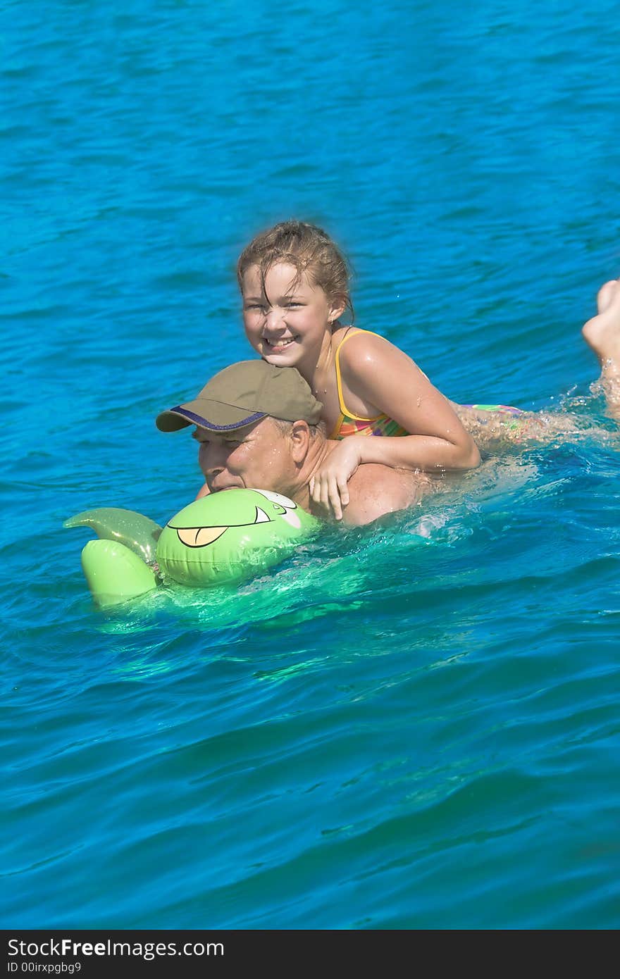 The grandfather swimming together with the granddaughter. The grandfather swimming together with the granddaughter