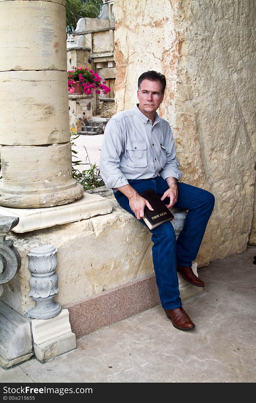 A man with a serious expression on his face, sitting with a bible in his hands. A man with a serious expression on his face, sitting with a bible in his hands.