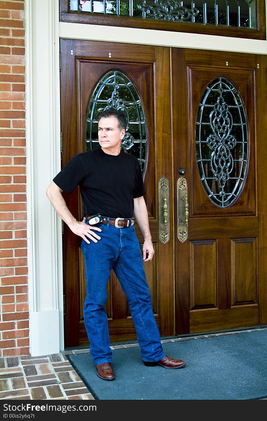 Man standing in front of beautiful wooden double doors with ornate glass work. Man standing in front of beautiful wooden double doors with ornate glass work.