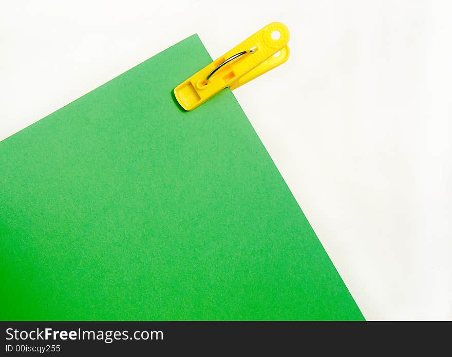 Bright yellow clip and piece of green paper in school or office stationery. Bright yellow clip and piece of green paper in school or office stationery