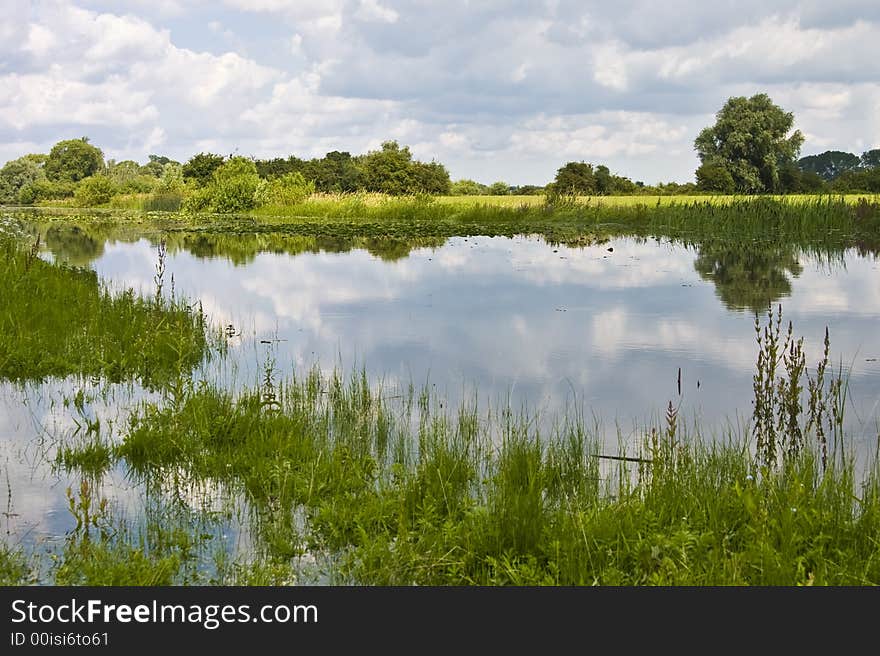 Landscape with calm lake and cloudy sky, reflected in the water. Landscape with calm lake and cloudy sky, reflected in the water