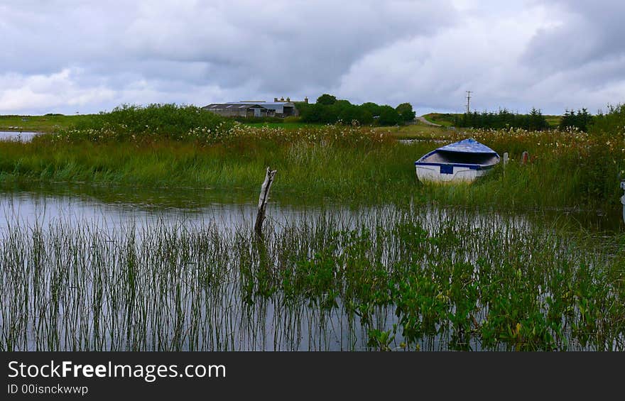 Loch Calder in the Scottish Highlands, peaceful under the approaching storm, with an old boat on the banks. Loch Calder in the Scottish Highlands, peaceful under the approaching storm, with an old boat on the banks