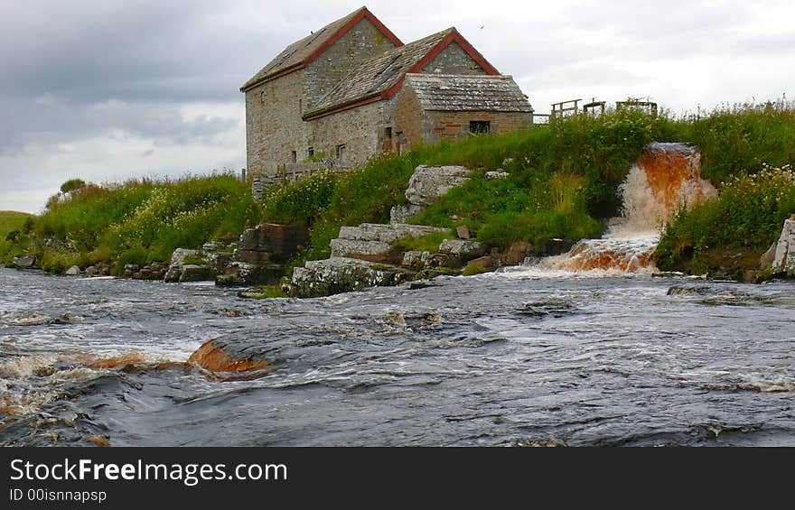 Old mill and water race in spate under storm clouds and in the rain. Old mill and water race in spate under storm clouds and in the rain.