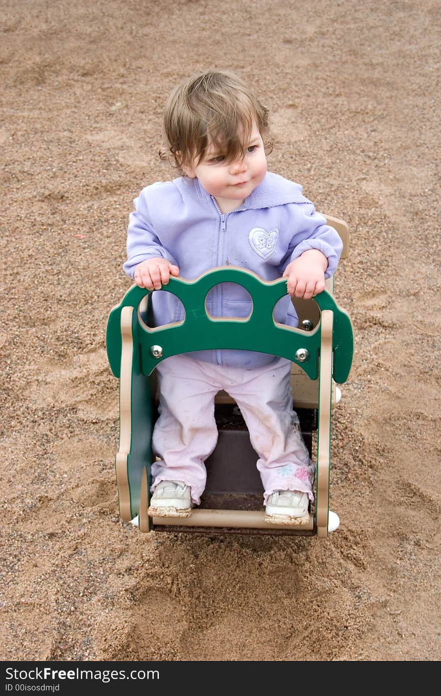 A little girl playing in a rocker in the park. A little girl playing in a rocker in the park