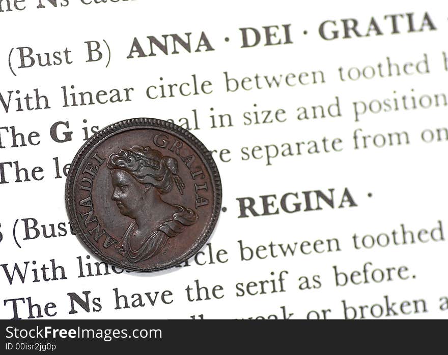 Rare copper Queen Anne farthing on the page of a coin book.