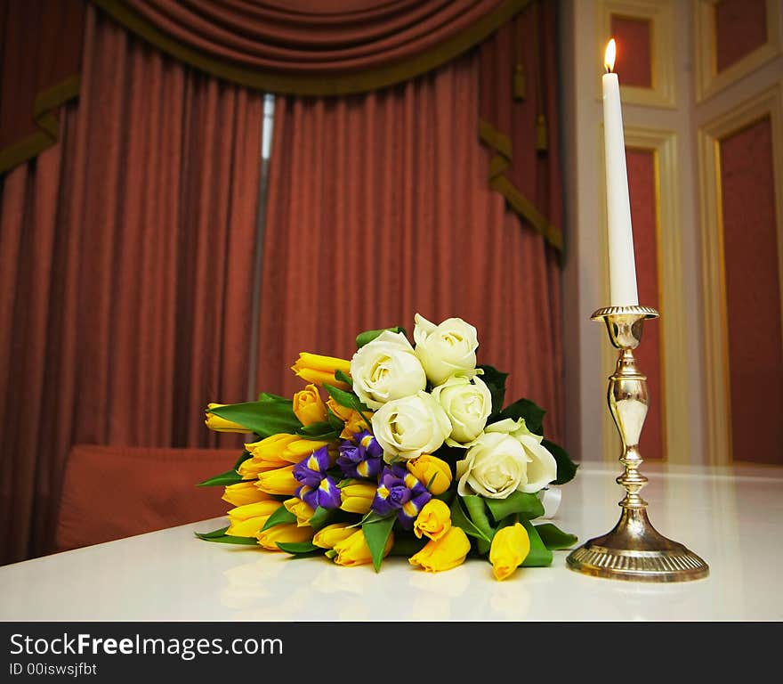 Bouquet with roses near a candle