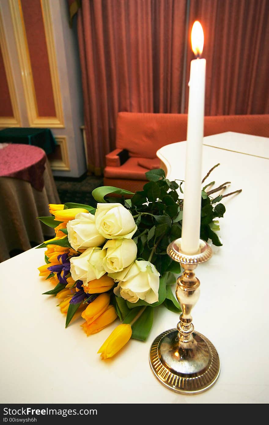 Bouquet with roses near a candle