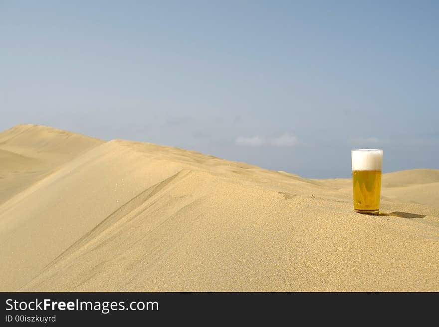 A glass of fresh beer in a desert. A glass of fresh beer in a desert.