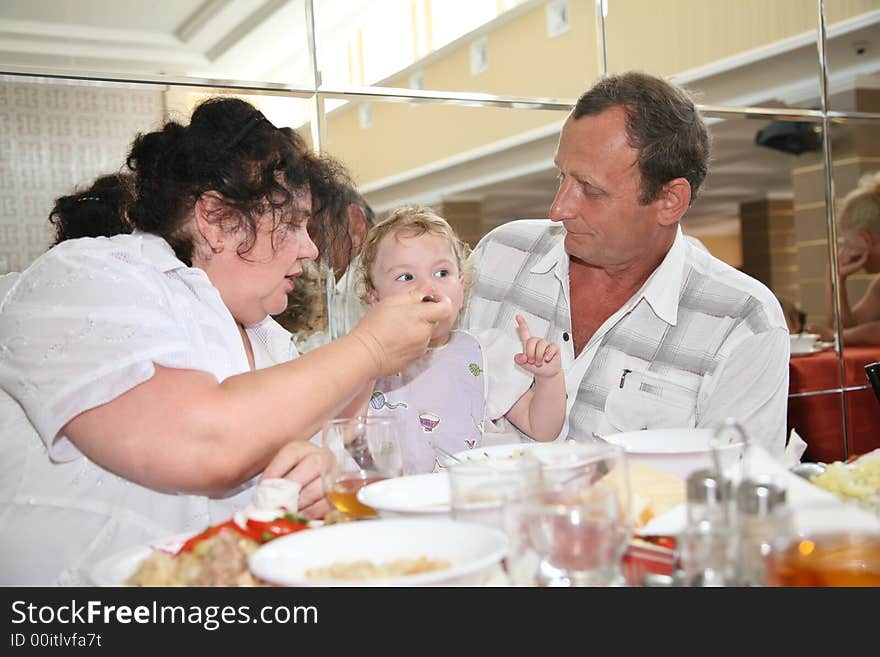 Grandmother with grandfather feeds child in canteen one. Grandmother with grandfather feeds child in canteen one