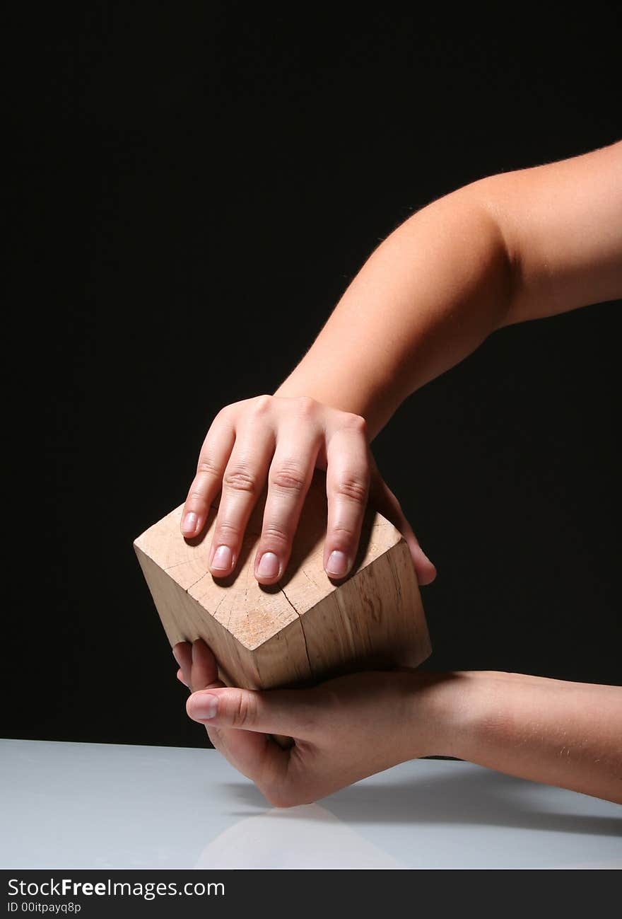 Hands holding a wooden cube infront of the black background. Hands holding a wooden cube infront of the black background