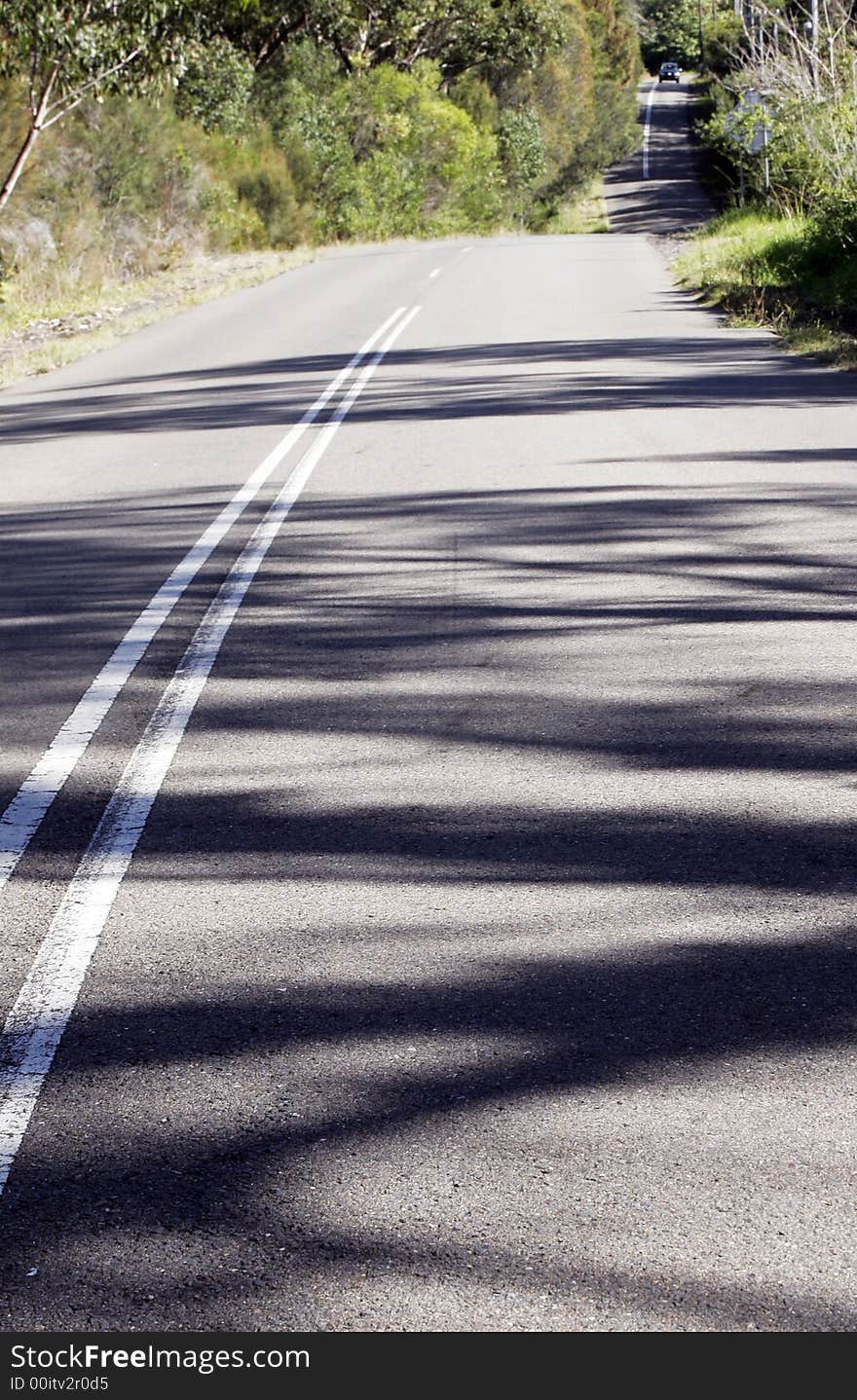 Asphalt Country Road Winding Down A Hill, Sunny Day, Shadows On Street