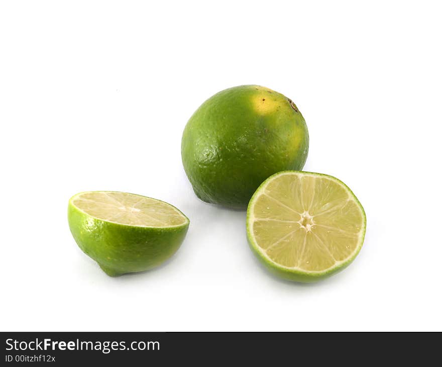 One green lime and two halves liyng on the white background