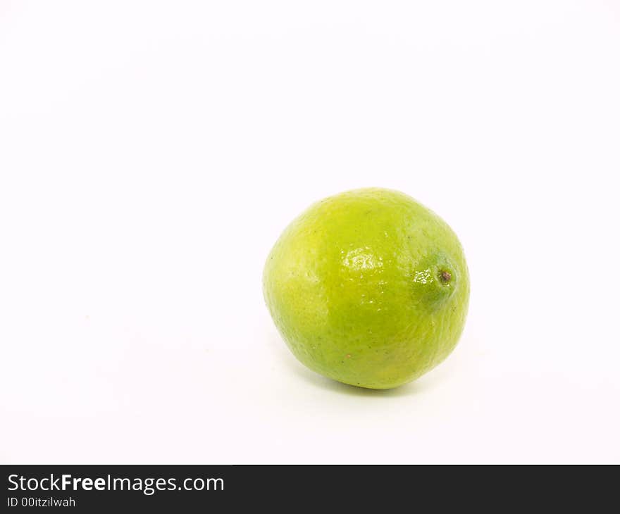 One green lime liyng on the white background. One green lime liyng on the white background