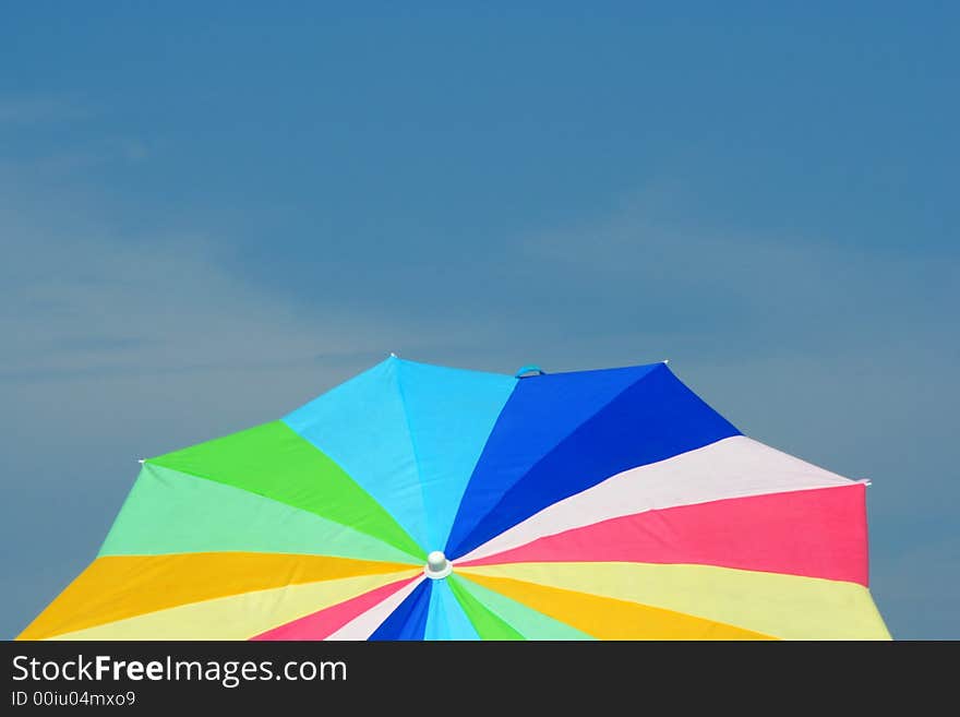 A Colorful Beach Umbrella is Framed against a Blue Sky. A Colorful Beach Umbrella is Framed against a Blue Sky.