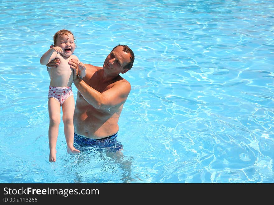 Grandfather standing in pool holds granddaughter. Grandfather standing in pool holds granddaughter