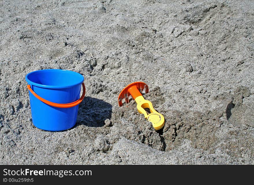 A bucket and rake in the sand at the beach