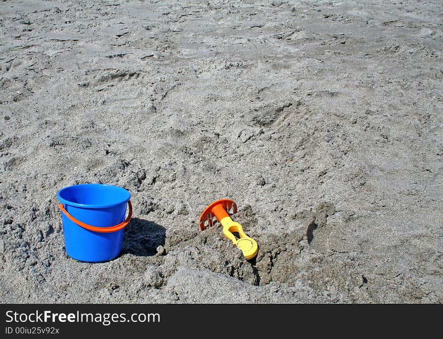 A bucket and rake on a beach. A bucket and rake on a beach