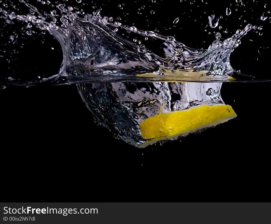 Splashing lemon into the water over black background