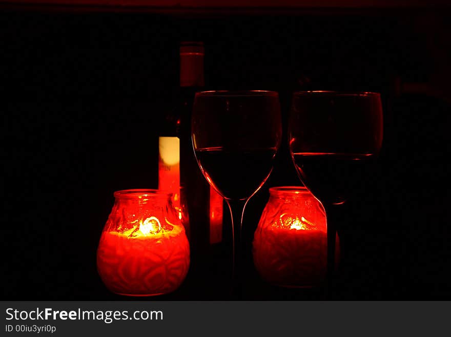 Two glasses with a red wine in an environment of red candles. Two glasses with a red wine in an environment of red candles