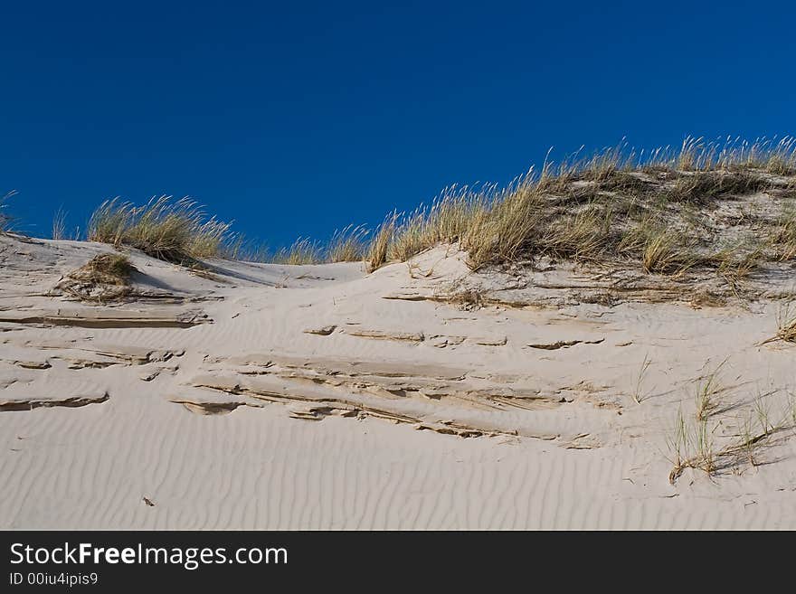 Sand-drift in the desert over blue sky