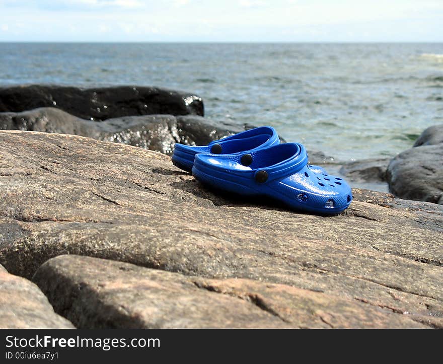 Blue clogs on a cliff by the ocean