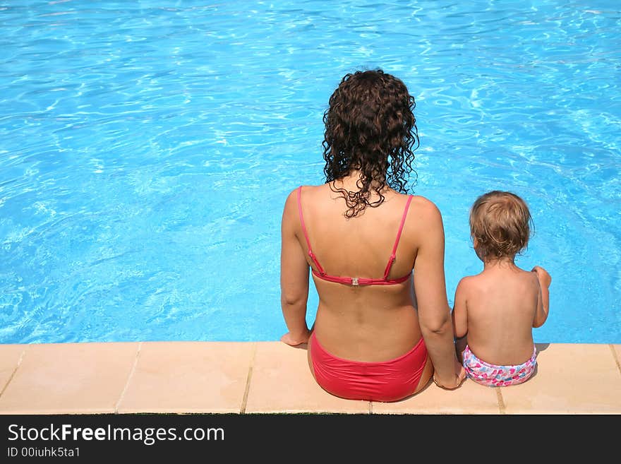 Mother and the daughter sit at pool