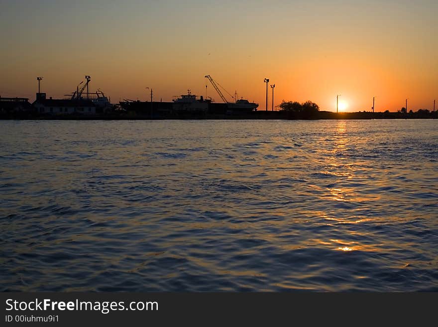 Sunrise on the Danube river,Sulina branch, with a building yard on the background. Sunrise on the Danube river,Sulina branch, with a building yard on the background