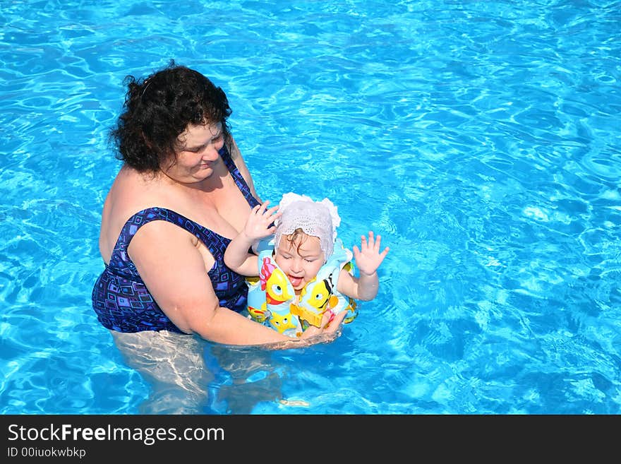 The grandmother plays with the granddaughter in pool. The grandmother plays with the granddaughter in pool