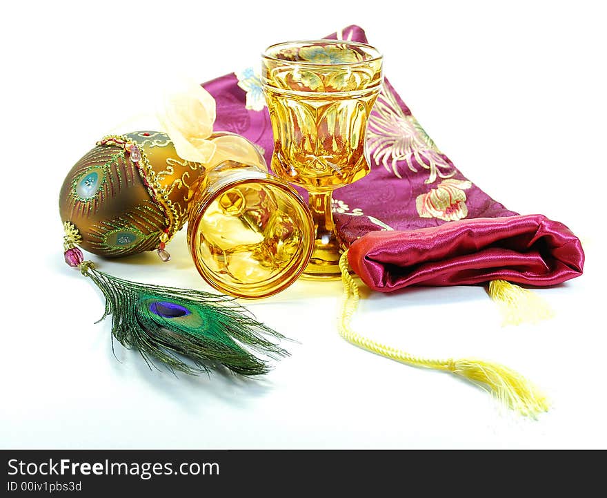 Decorated egg peacock feather drinking glasses and bag still life