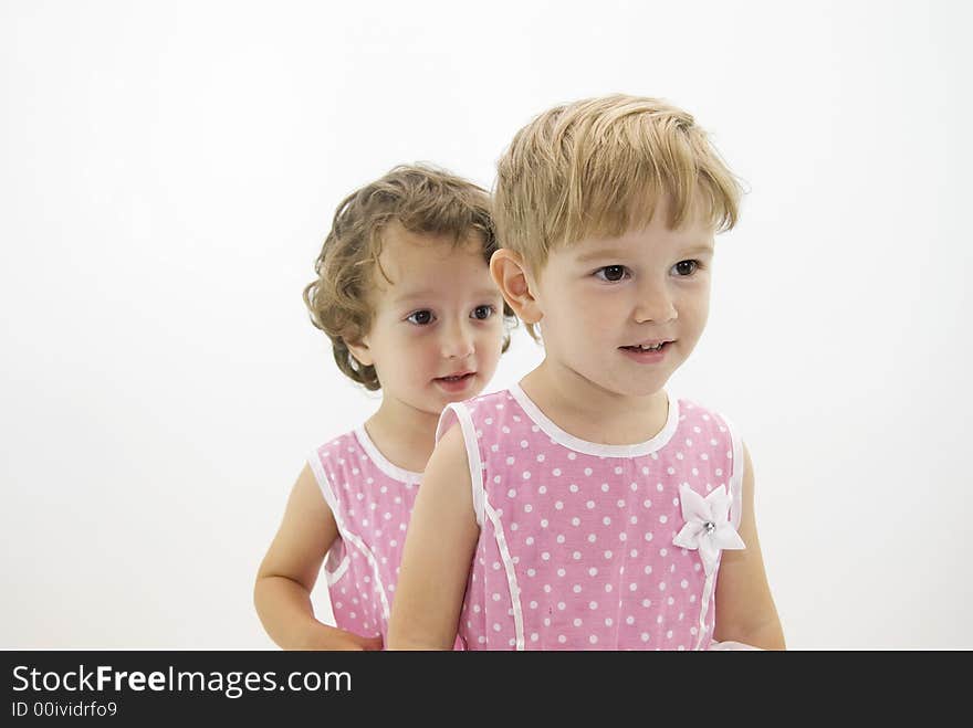 Twins sisters in pink dresses playing in the studio. Twins sisters in pink dresses playing in the studio