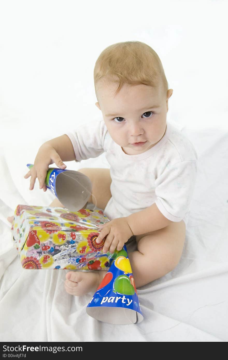 Cute baby boy looking up and opening his birthday gift. Cute baby boy looking up and opening his birthday gift