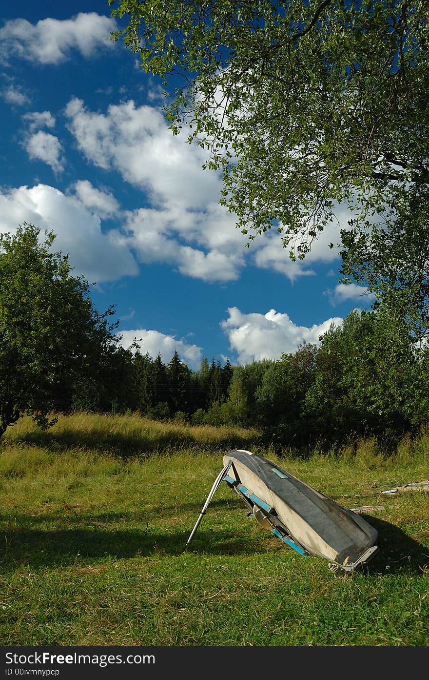 An old kayak resting on the edge under the deep blue sky full of beautiful clouds