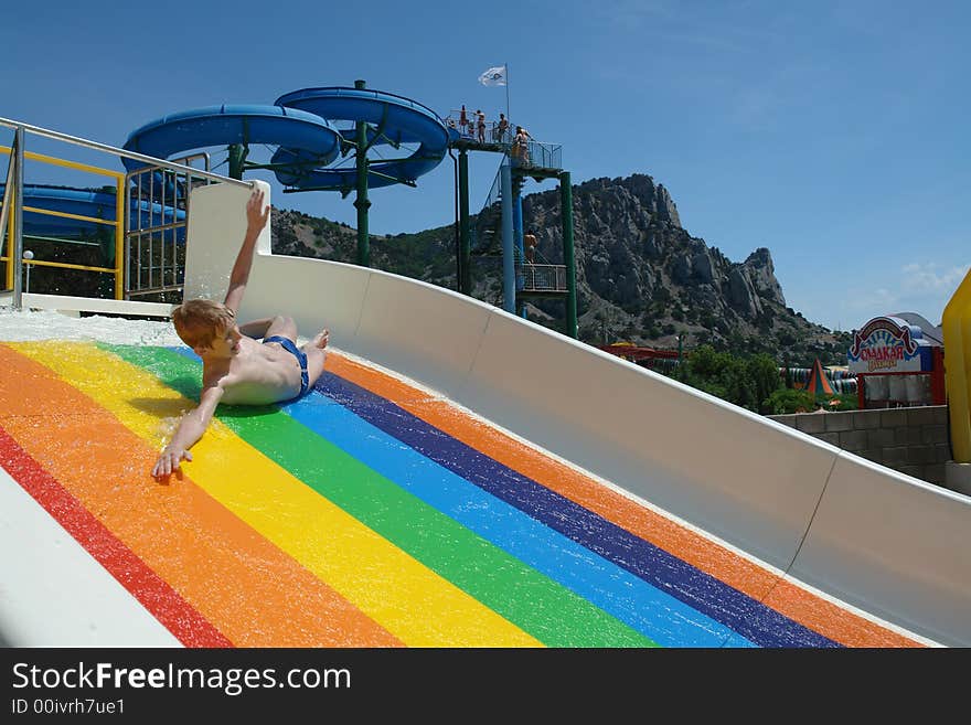 The boy goes down from a waterslide in an aquapark. The boy goes down from a waterslide in an aquapark.