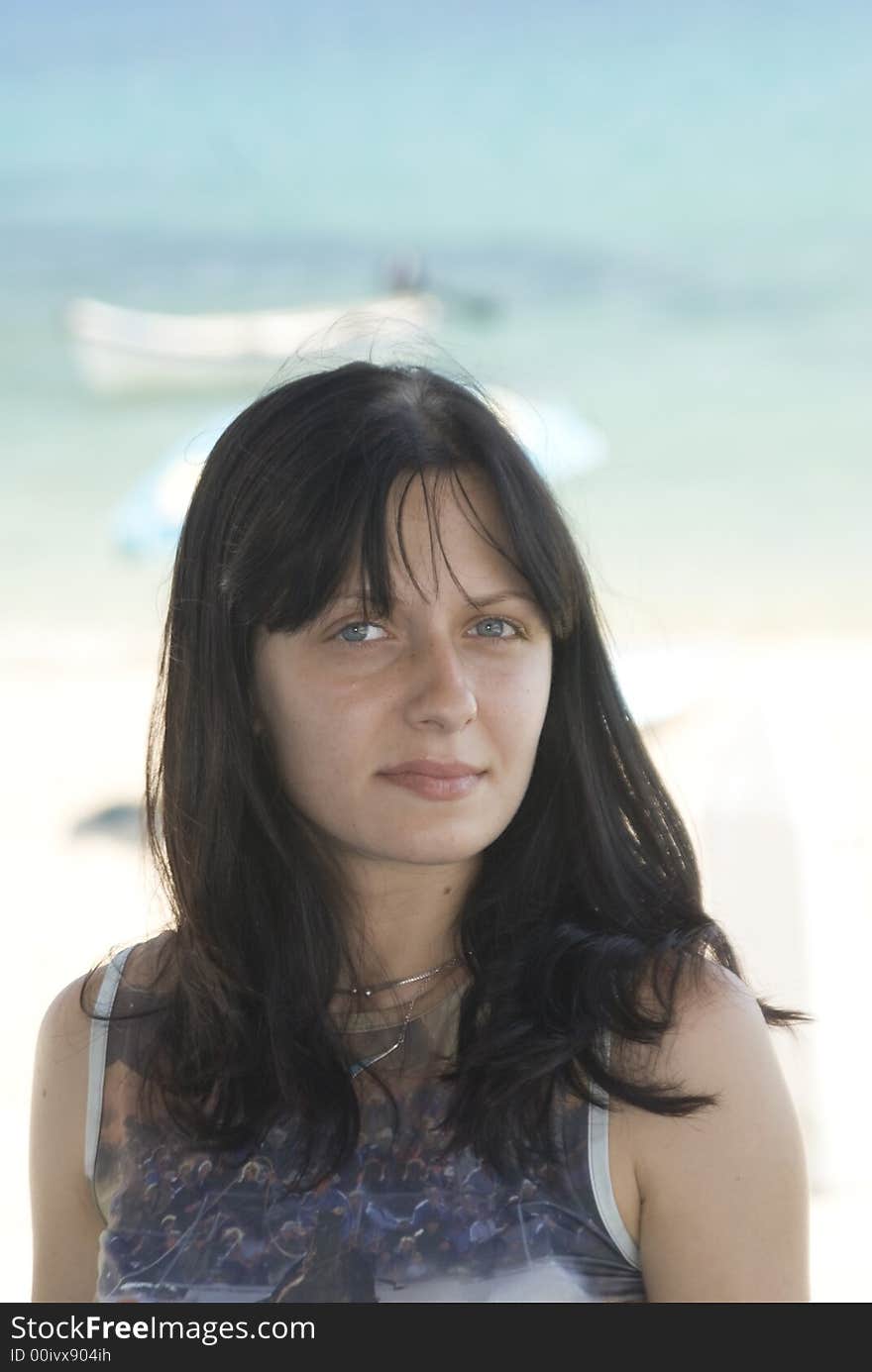 Attractive young woman with slight smile beach and boats in background. Attractive young woman with slight smile beach and boats in background