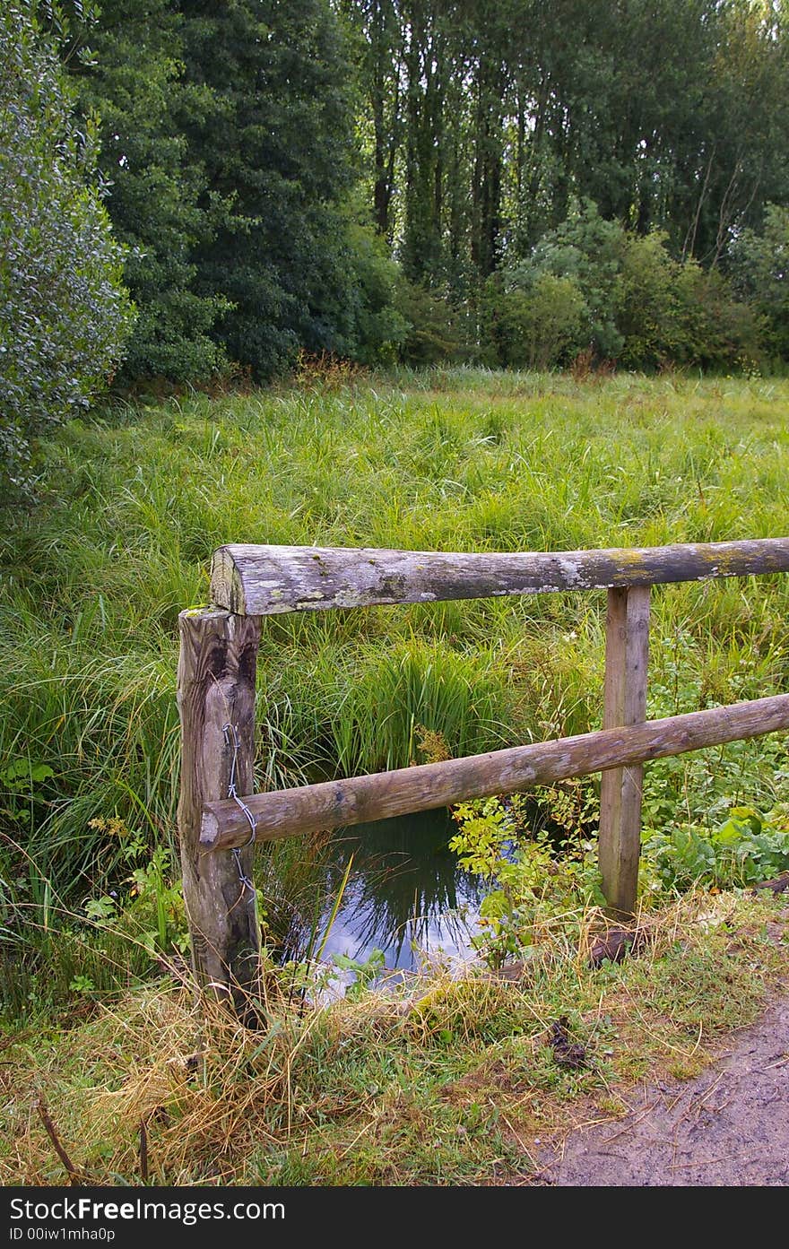 Wooden fence along a marsh (with reflection in water). Wooden fence along a marsh (with reflection in water).