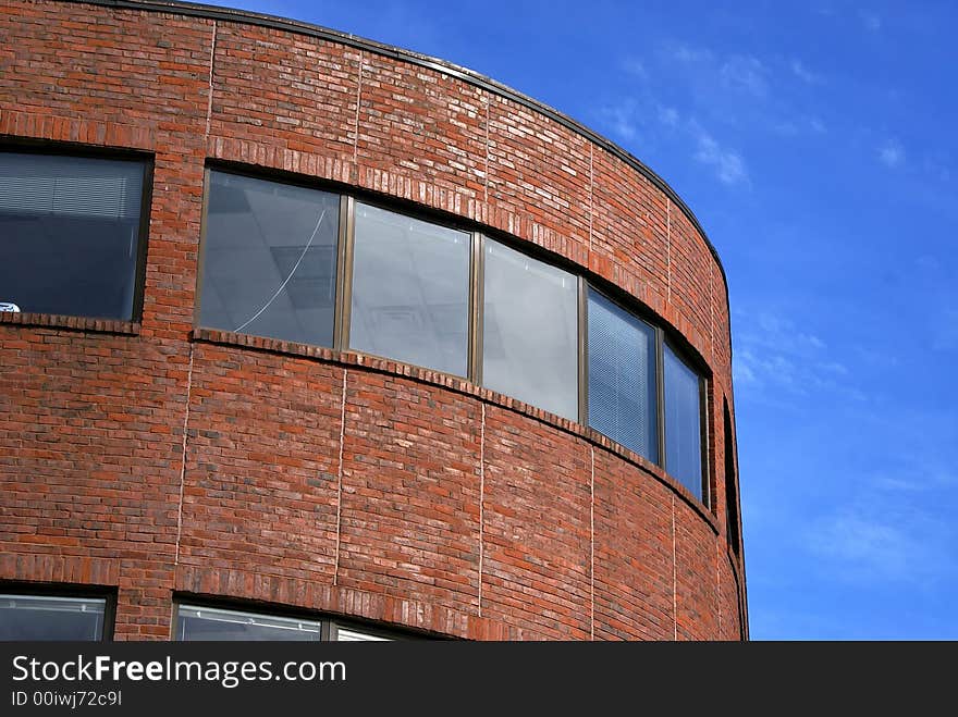 Majestic yet simple curved brick building  against a light blue sky with soft clouds located in harvard square, cambridge massachusetts. Majestic yet simple curved brick building  against a light blue sky with soft clouds located in harvard square, cambridge massachusetts