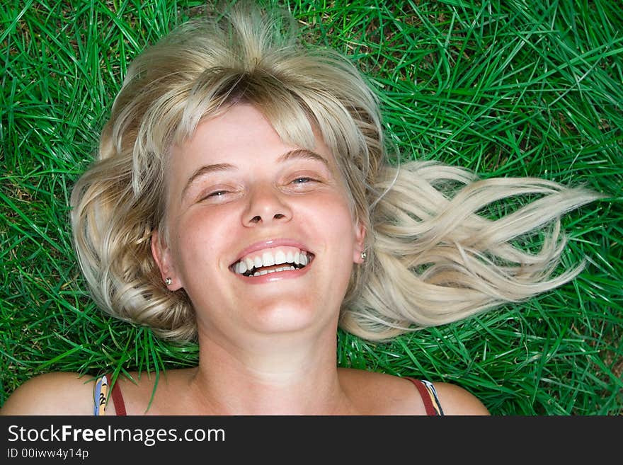 Beauty blonde happy woman lie on green grass