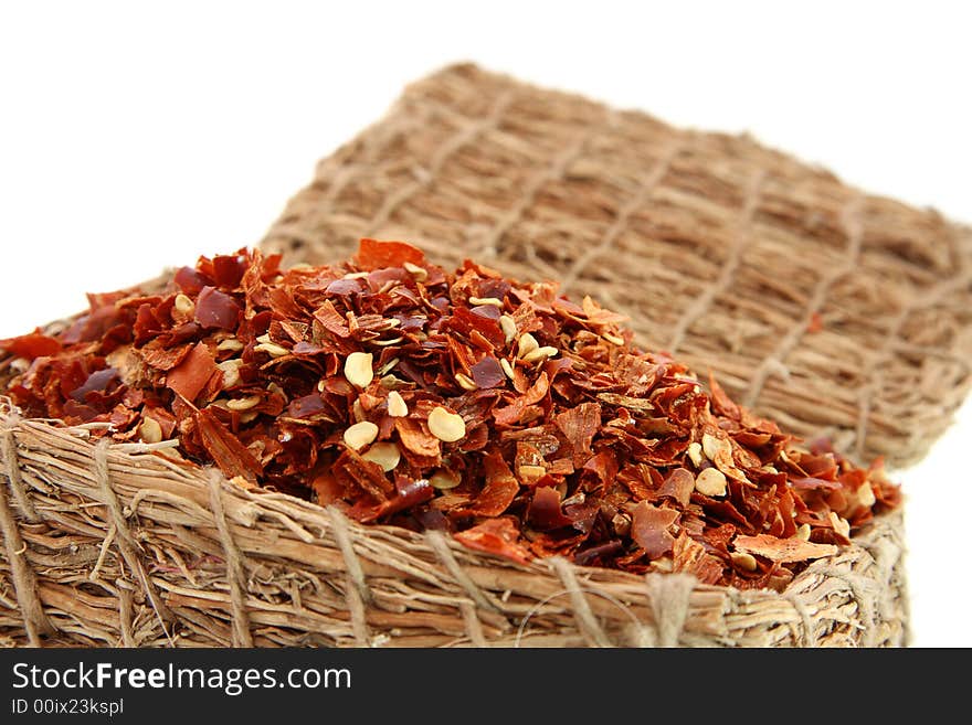 Crashed Red Hot Chilli Pepper in wooden straw box, isolated on white, no shadow, soft focus.