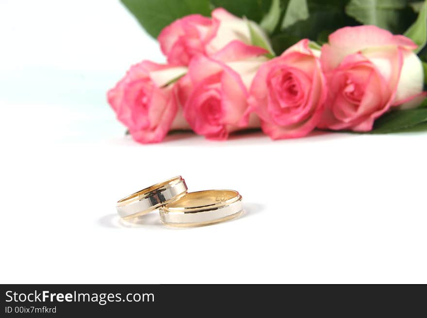 Wedding rings and roses on white background