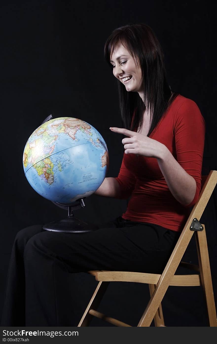 Pretty girl pointing at the globe, black background. Pretty girl pointing at the globe, black background