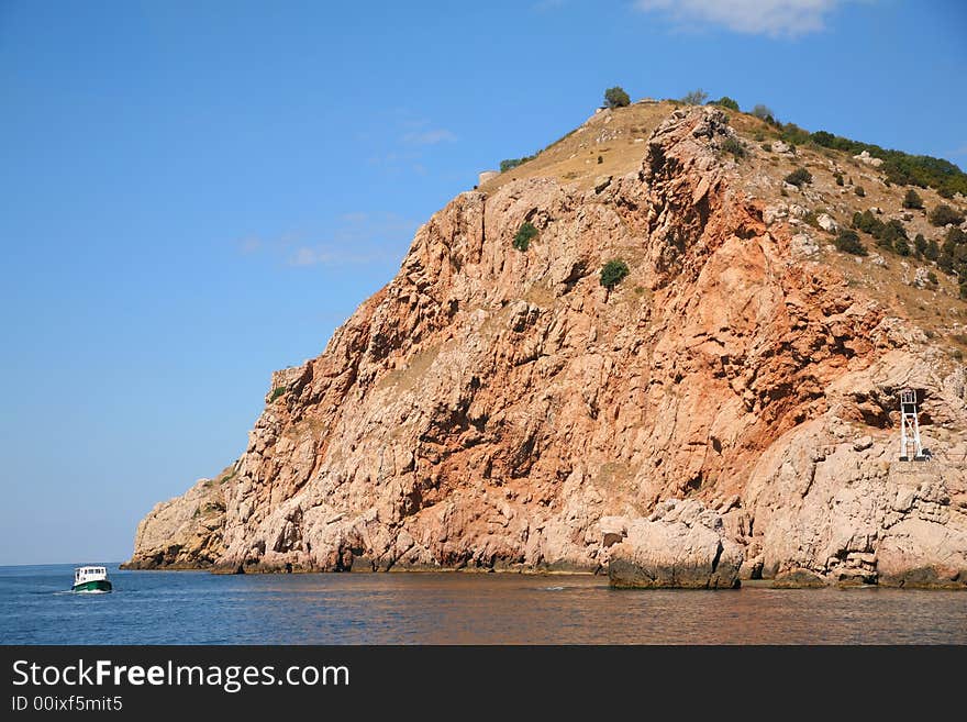 The small ship sail near the cliff in Crimea