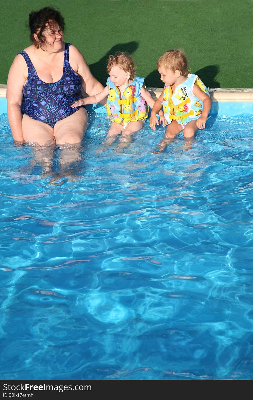 The grandmother and children sit at pool.