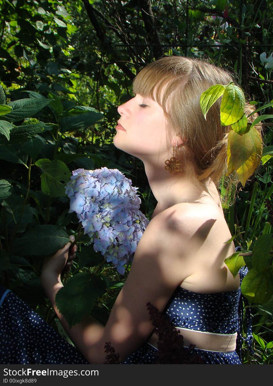 The young girl is in a garden. In a garden the fine blue flower blossoms. It enjoys this flower. The young girl is in a garden. In a garden the fine blue flower blossoms. It enjoys this flower.