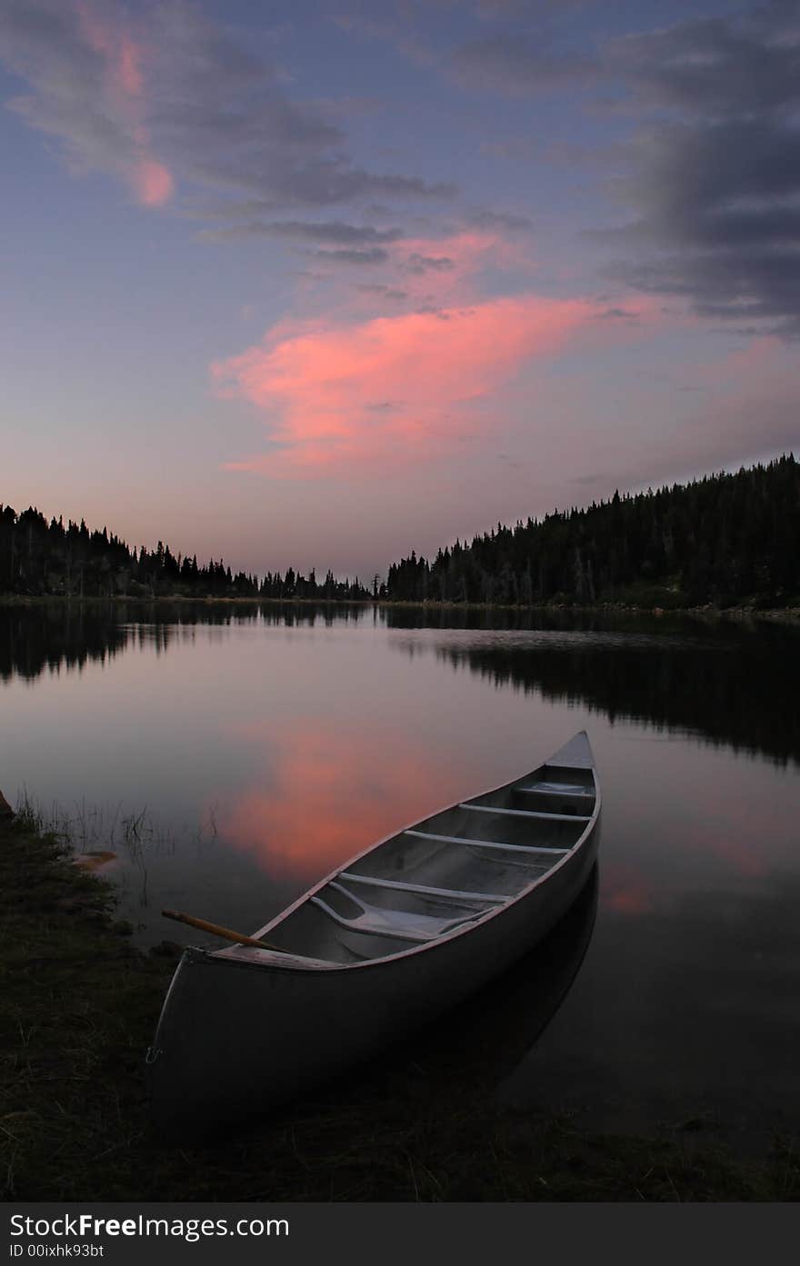 Evening sunset in soft pink and blue light and canoe in lake. Evening sunset in soft pink and blue light and canoe in lake