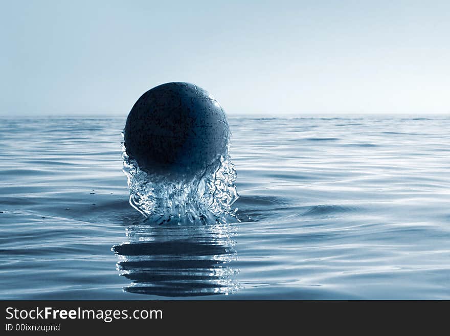 Emersion of black ball on a background of an evening seascape(cyan toned). Emersion of black ball on a background of an evening seascape(cyan toned)