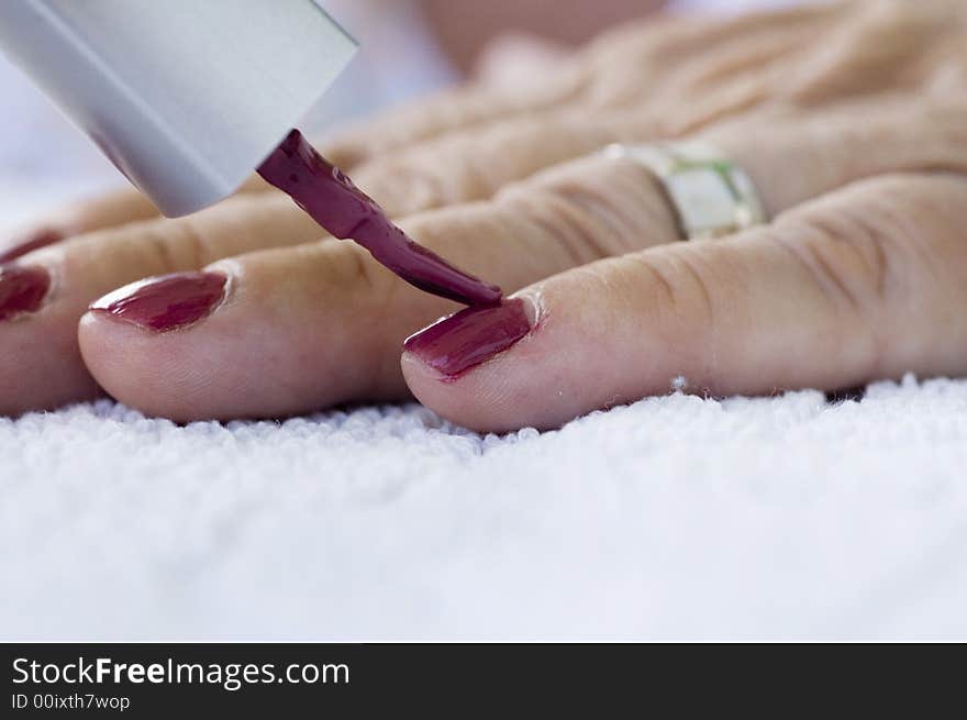 Elderly lady applies dark pink nailpolish to her fingernails. Elderly lady applies dark pink nailpolish to her fingernails