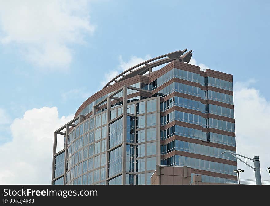 A modern curved brick and glass office building against the sky. A modern curved brick and glass office building against the sky