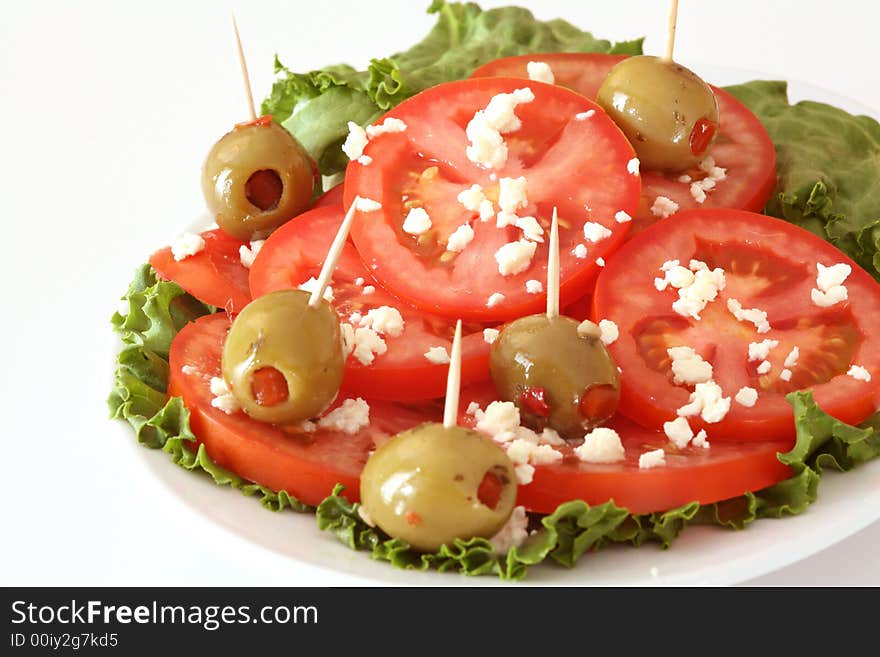 Tomato, feta cheese, olives and lettuce salad over the white background. Tomato, feta cheese, olives and lettuce salad over the white background